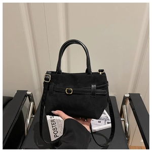 Détail du sac fourre-tout en daim noir avec poignées en cuir, boucles dorées et bandoulière