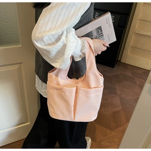 Détail du sac cabas en nylon rose avec deux poches avant et larges bretelles souples