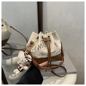 Detail of canvas bucket bag with graffiti pattern and cute white plush cat charm