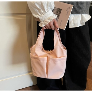 Détail d'un sac cabas en nylon rose pâle avec des poches avant fonctionnelles et poignée
