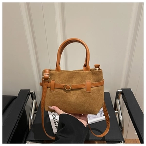 Détail de la texture en daim marron et boucle de sangle en cuir sur le grand sac cabas