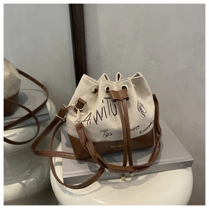Detail shot of vintage beige bucket bag with dark brown straps and cherry print
