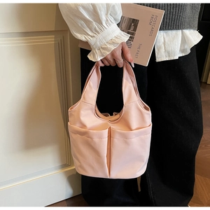 Gros plan d'un sac à main rose en nylon avec doubles poches avant et texture douce