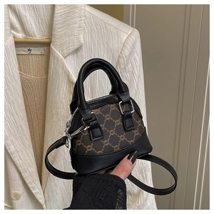 Detail of a brown shell handbag with vintage pattern and black leather handles in a daily outfit