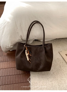 Detail of dark brown matte leather tote bag with colorful beaded tassel charm