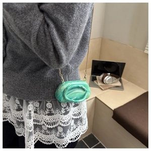 Detail of green marble acrylic evening bag with gold chain strap on model shoulder