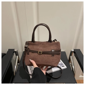 Détail du sac cabas en daim marron avec garniture en cuir et boucles métalliques dorées