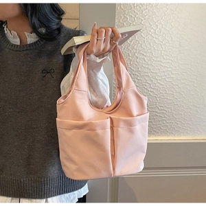 Gros plan d'un sac seau en nylon rose avec deux poches avant porté par un mannequin