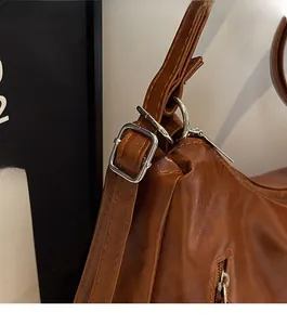 Detail of silver square buckle and zipper on brown leather multi-functional bag