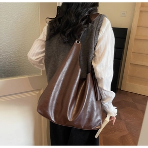 Detail of dark brown faux leather tote bag with silver eyelets on a model's shoulder