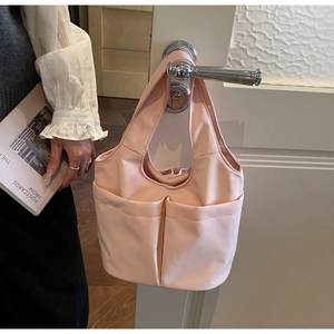 Gros plan d'un cabas en nylon rose clair avec doubles poches suspendu à une poignée