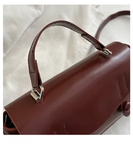 Close-up of wine red leather handbag featuring smooth texture and silver hardware