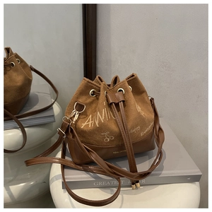 Detail of brown bucket bag featuring cherry embroidery and stylish drawstring closure