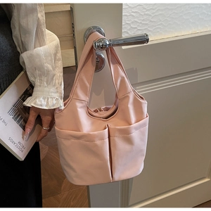 Détail d'un sac cabas en nylon rose avec poches latérales suspendu à une poignée de porte