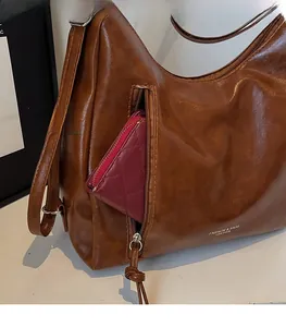 Detail view of a vintage brown tote bag featuring a front zipper pocket and gold logo