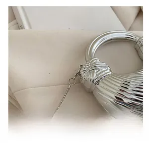 Dettaglio di pochette argento con trama a onde, manico ad anello e catena