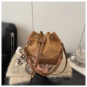 Detail of a brown fuzzy plush shoulder bag with a leopard bow bear charm and drawstring