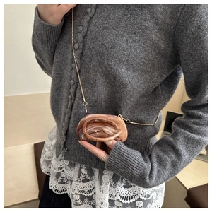 Detailed shot of amber marble mini bag with golden chain and circular resin handle