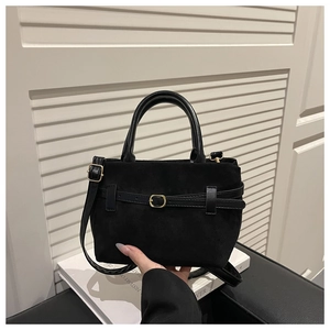 Détail du sac seau en daim noir avec boucle décorative et ferrures en métal doré élégant
