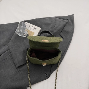 Quilted green crossbody bag with chain strap and gold clasp on a gray blazer