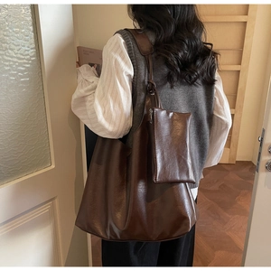 Detail of dark brown tote bag with matching pouch on model in minimal interior