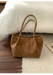 Detail of a brown vintage tote bag with matte texture on a soft white plush rug