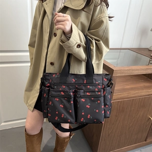 Grand sac cabas en nylon noir à imprimé cerises porté par un mannequin dans un cadre intérieur