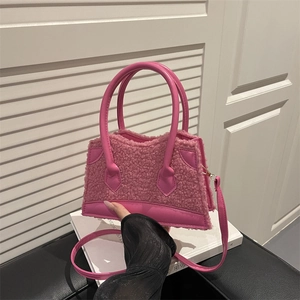 Mini sac bandoulière en laine d'agneau rose avec poignées en cuir sur un livre