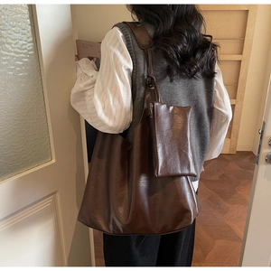Detail view of large dark brown leather tote bag with matching mini zip pouch attachment