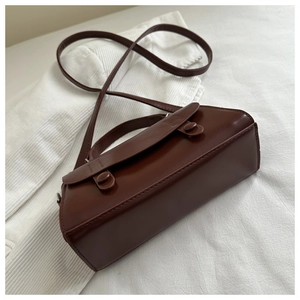 Detail view of the deep red vintage crossbody bag showing side structure and wide base