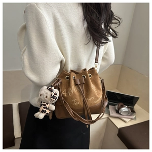Brown suede bucket bag with hand-drawn graffiti and a cute cat charm in a daily setting