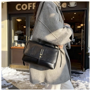 Détail du sac bandoulière vintage noir avec texture plissée et boucle en métal en hiver