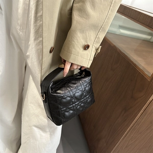 Quilted heart pattern black PU leather crossbody bag with gold hardware held by a model