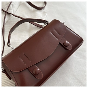 Detailed view of deep coffee retro handbag with smooth matte finish and decorative stitching