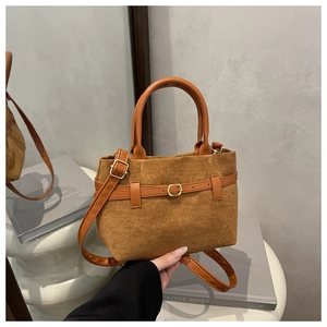 Détail d'un sac seau en daim marron avec anses en cuir orange et boucle dorée élégante