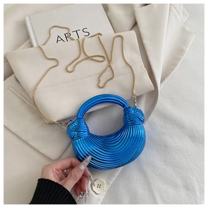 Détail macro du sac croissant bleu électrique avec texture spirale et chaîne dorée