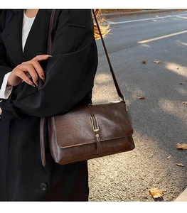 Dettaglio della borsa a tracolla vintage in finta pelle marrone scuro con fibbia d'oro