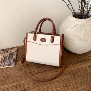 Détail d'un sac à main bicolore blanc et marron avec une bandoulière longue et amovible
