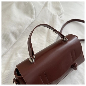 Detailed macro shot of the dark brown leather handbag handle and silver metallic buckle