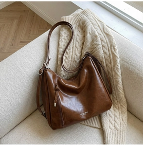Detailed view of deep brown vintage faux leather shoulder bag with side zipper on sofa