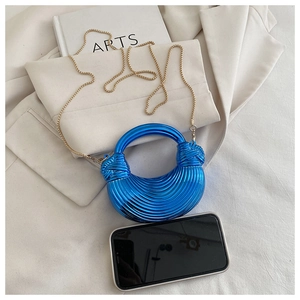 Détail du sac croissant bleu métallique avec texture gaufrée et fine chaîne dorée