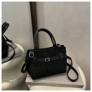 Détail du sac seau noir en daim mat avec boucle dorée et bandoulière réglable
