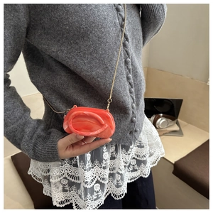 Close-up of bright orange marble acrylic mini bag with fine gold metal chain strap