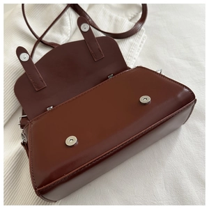 Detail view of deep brown leather bag showing magnetic closures and neat stitching