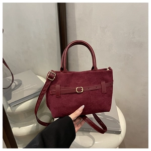 Détail du sac seau bordeaux en daim avec boucle dorée et bandoulière en cuir