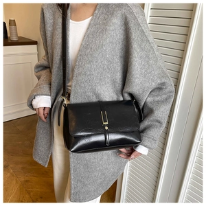 Gros plan d'un sac bandoulière en cuir noir avec boucle métallique dorée élégante