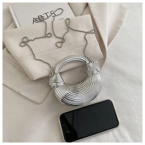 Comparaison de taille d'une pochette demi-lune argentée avec téléphone sur tissu doux