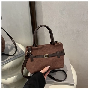 Détails de la texture en daim marron foncé et de la boucle en cuir sur le sac à main