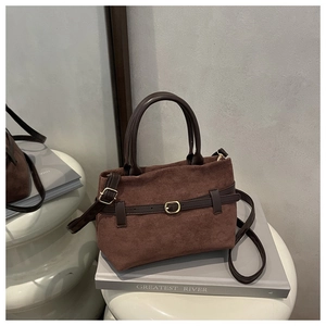 Détail du sac seau en daim marron foncé avec boucle de ceinture en cuir et ferrures dorées
