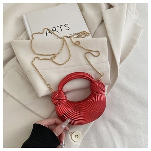 Détail du sac croissant rouge métallique avec texture circulaire et bandoulière dorée